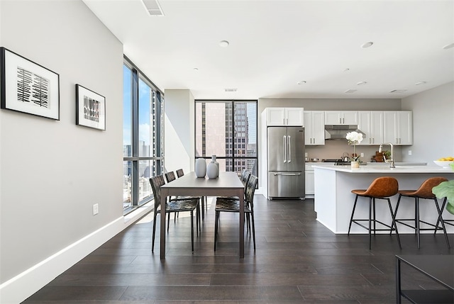 dining room with dark wood-type flooring, expansive windows, and sink