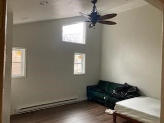 unfurnished room with hardwood / wood-style flooring, a baseboard heating unit, and ceiling fan