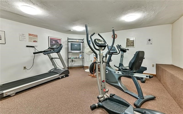 exercise room featuring a textured ceiling and carpet floors