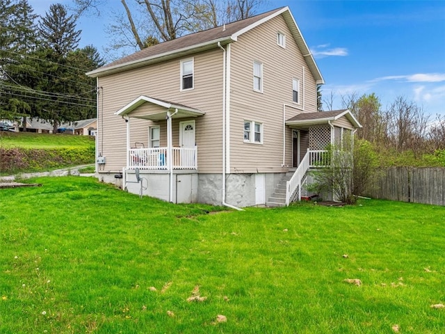 back of house featuring covered porch and a lawn