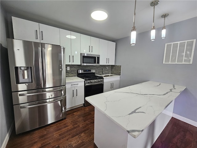 kitchen with hanging light fixtures, stainless steel appliances, tasteful backsplash, dark wood-type flooring, and white cabinetry