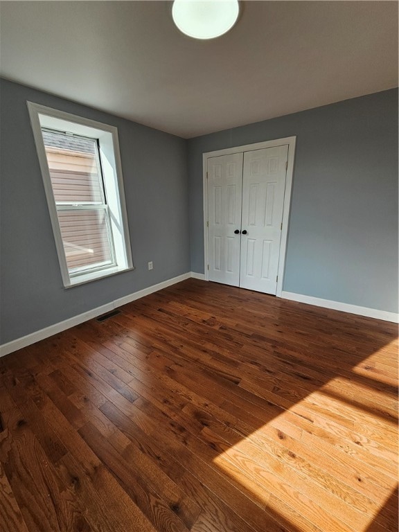 unfurnished bedroom featuring a closet and dark hardwood / wood-style floors