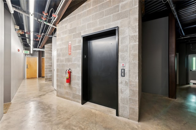 hall featuring concrete flooring and elevator