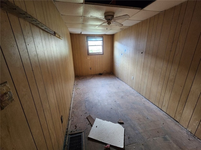 spare room with wood walls, ceiling fan, and a drop ceiling