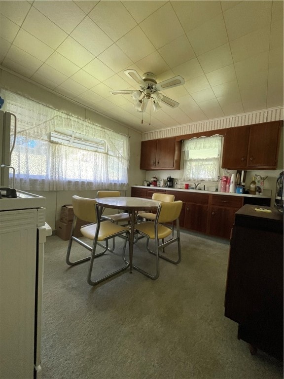 carpeted dining space featuring sink and ceiling fan