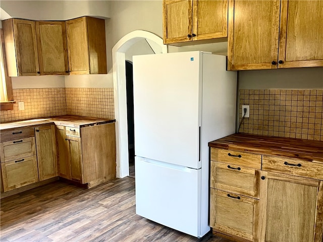 kitchen featuring wood counters, tasteful backsplash, wood-type flooring, and white refrigerator