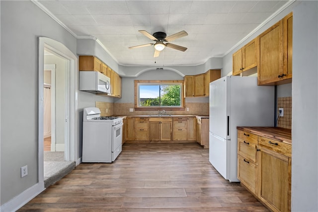 kitchen featuring decorative backsplash, hardwood / wood-style flooring, ornamental molding, sink, and white appliances