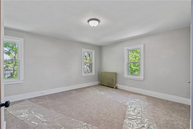 carpeted spare room featuring radiator heating unit