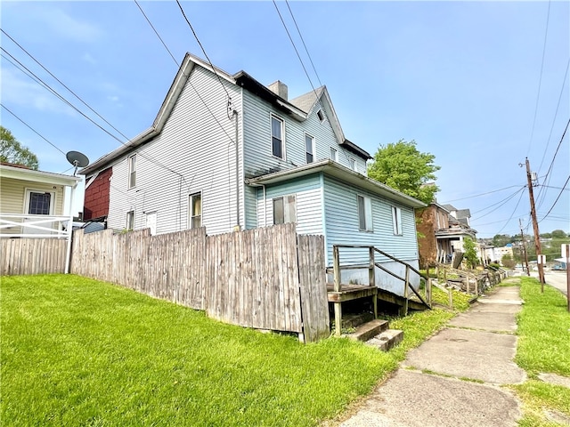 view of side of home featuring a yard and a wooden deck