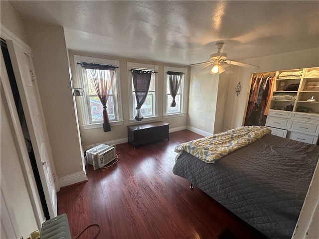 bedroom with a wall mounted AC, ceiling fan, and dark wood-type flooring