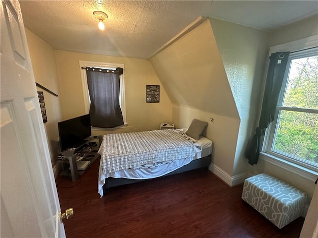 bedroom with a textured ceiling, lofted ceiling, and dark hardwood / wood-style floors