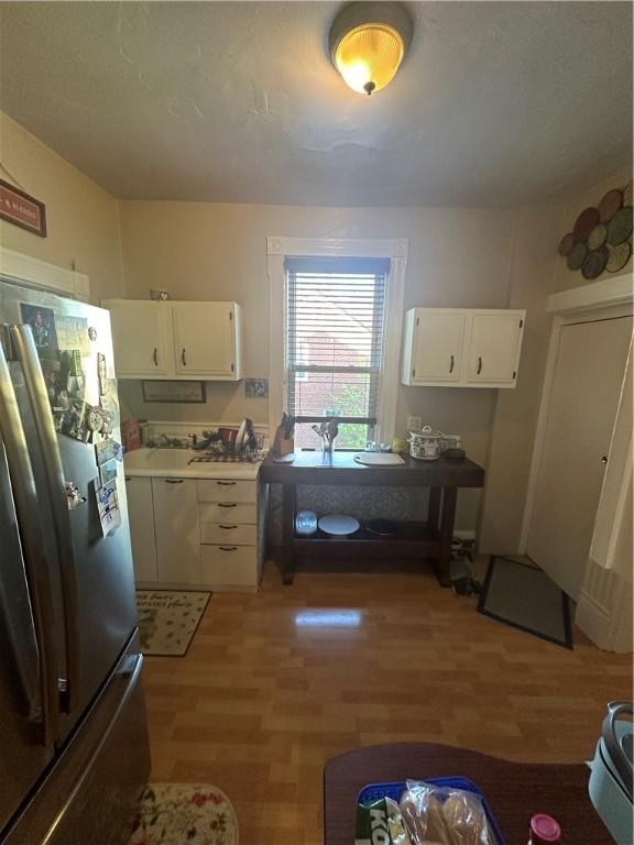 kitchen featuring white cabinets, hardwood / wood-style floors, and stainless steel refrigerator