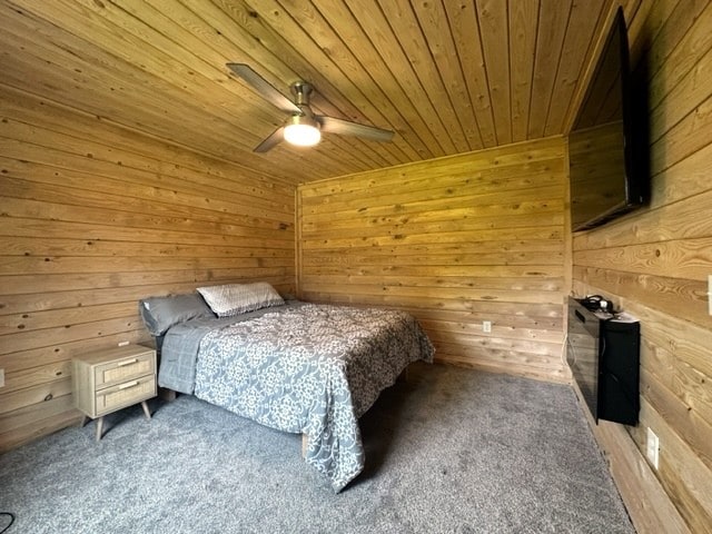 unfurnished bedroom featuring carpet floors, wood walls, ceiling fan, and wooden ceiling