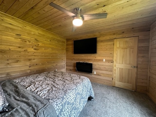 carpeted bedroom with wood ceiling, ceiling fan, and wooden walls