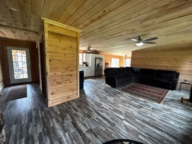 interior space with wooden ceiling, ceiling fan, dark hardwood / wood-style flooring, and wooden walls