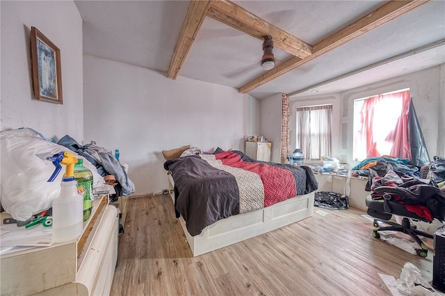 bedroom featuring hardwood / wood-style floors, beam ceiling, and ceiling fan