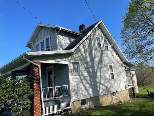 view of property exterior featuring covered porch and a lawn