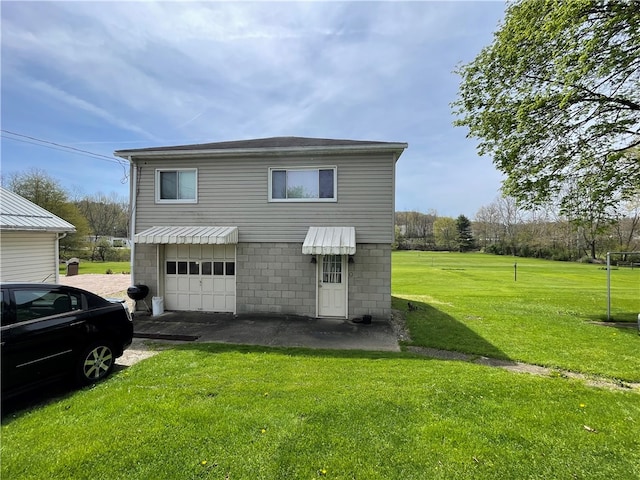 rear view of property featuring a yard and a garage