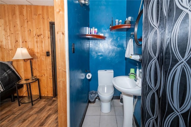 bathroom with wood walls, wood finished floors, and toilet