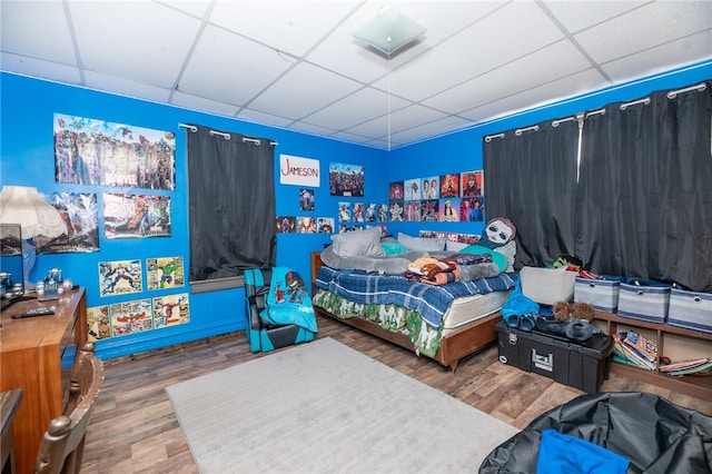 bedroom featuring wood finished floors and a paneled ceiling