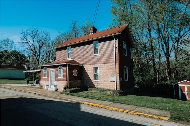 view of front facade featuring an outbuilding, stone siding, a storage unit, a chimney, and a front yard