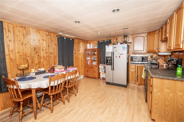 dining space featuring light wood finished floors and wooden walls