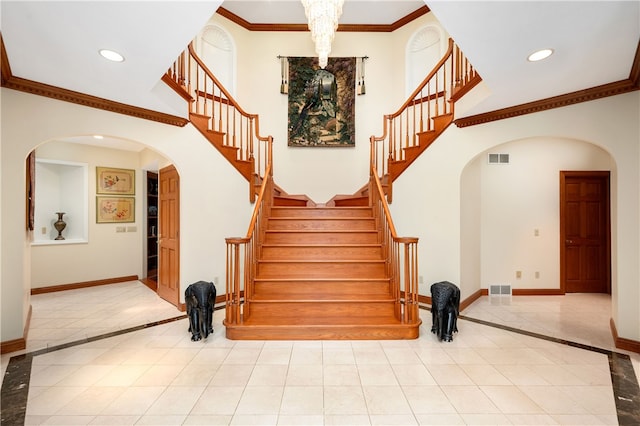 staircase featuring a chandelier, light tile floors, and crown molding