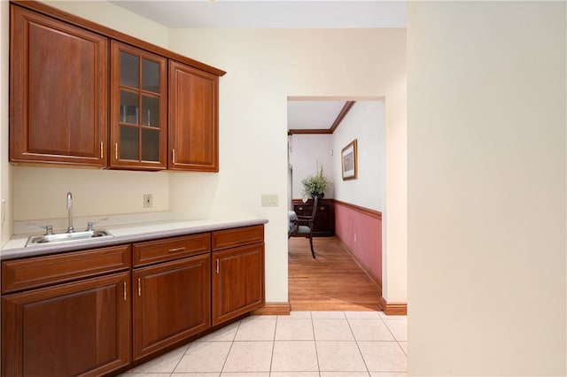 kitchen featuring sink, ornamental molding, and light tile flooring