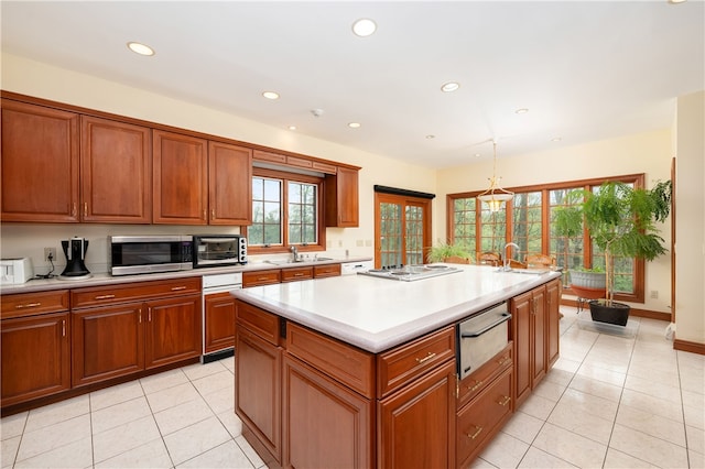 kitchen with hanging light fixtures, sink, an island with sink, and light tile flooring