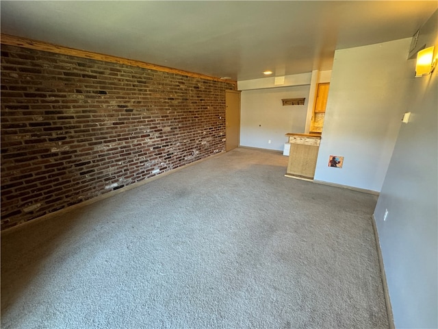 unfurnished living room with carpet floors and brick wall