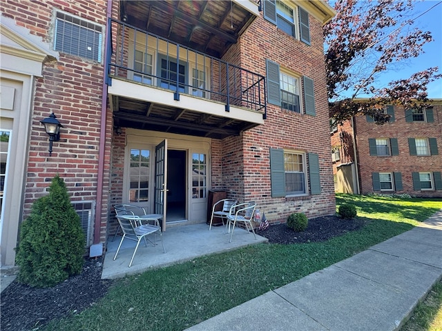 property entrance with a patio, a balcony, and a yard