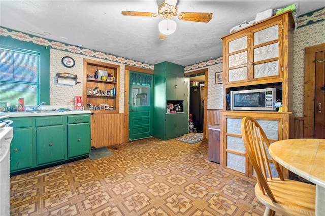 kitchen featuring light parquet floors, stainless steel microwave, green cabinetry, ceiling fan, and a textured ceiling