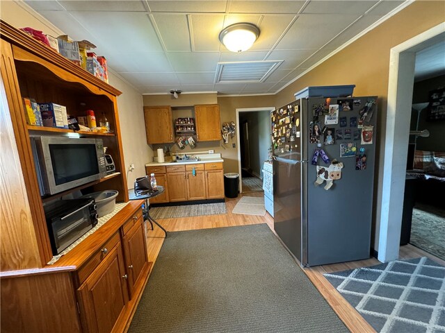 kitchen with light hardwood / wood-style flooring, ornamental molding, and appliances with stainless steel finishes