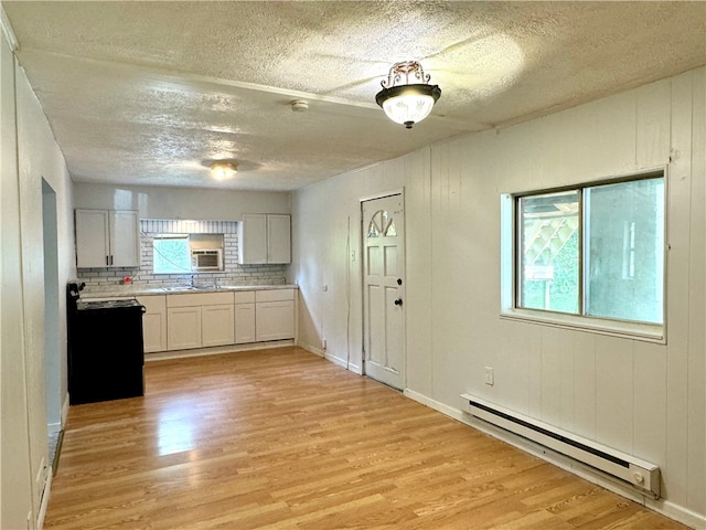 kitchen with a textured ceiling, white cabinetry, backsplash, baseboard heating, and light hardwood / wood-style floors