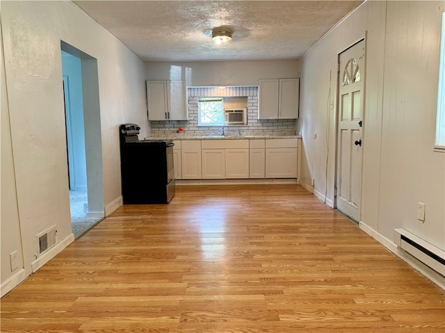 kitchen featuring stainless steel electric stove, backsplash, light hardwood / wood-style floors, white cabinetry, and baseboard heating