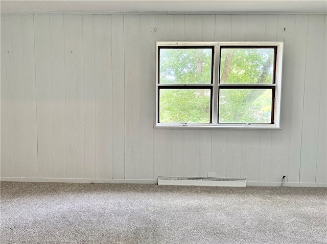 unfurnished room with plenty of natural light, baseboard heating, carpet, and wooden walls