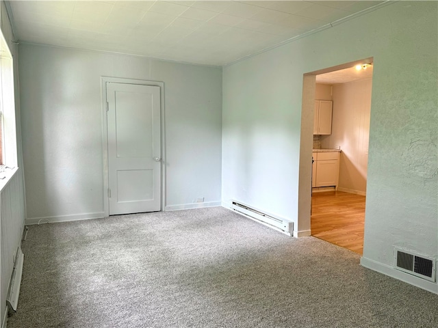 carpeted empty room featuring baseboard heating