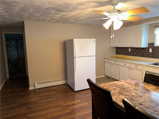 kitchen featuring backsplash, white cabinetry, dark wood-type flooring, white refrigerator, and baseboard heating