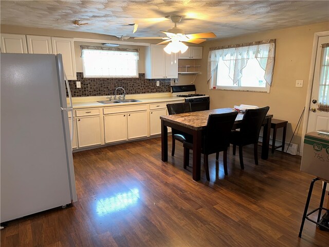 dining area featuring ceiling fan, a wealth of natural light, dark wood-type flooring, and sink