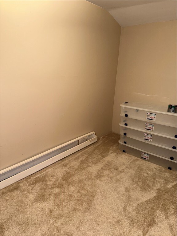 spare room featuring vaulted ceiling, carpet, and a baseboard radiator