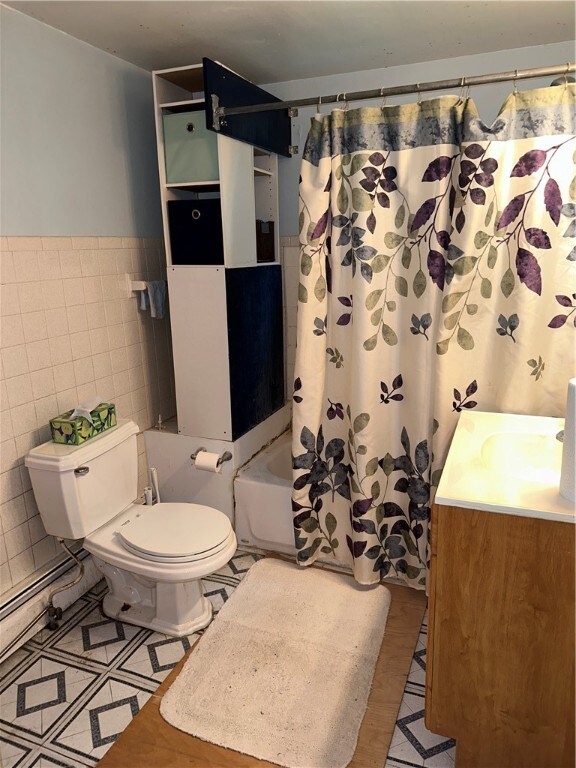 full bathroom with tile walls, vanity, shower / bathtub combination with curtain, and toilet