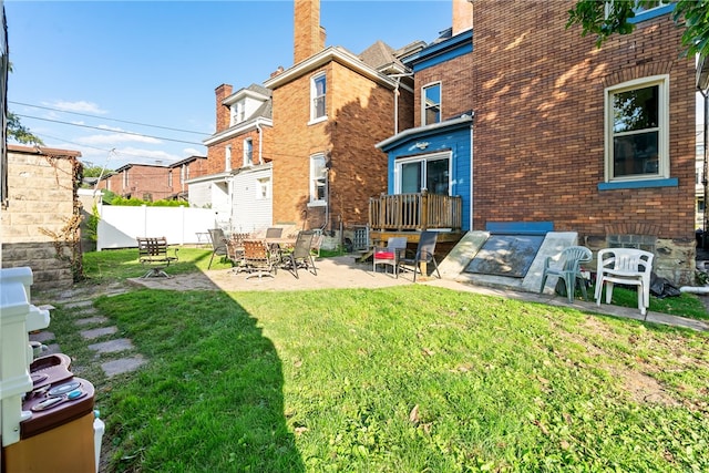 back of house with a patio and a lawn