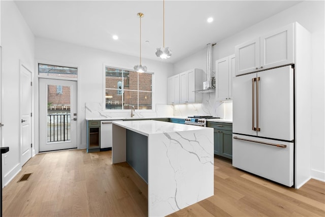 kitchen with a center island, white appliances, backsplash, hanging light fixtures, and light hardwood / wood-style flooring