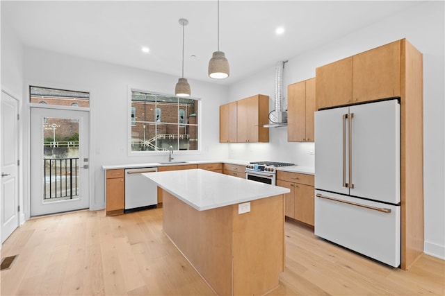 kitchen with a center island, hanging light fixtures, white appliances, light hardwood / wood-style flooring, and sink