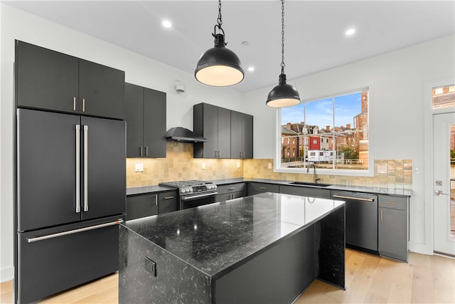 kitchen featuring wall chimney exhaust hood, a kitchen island, high quality appliances, tasteful backsplash, and decorative light fixtures