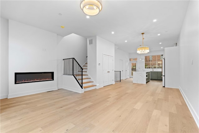 unfurnished living room with a notable chandelier and light wood-type flooring