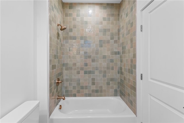 bathroom featuring tiled shower / bath and toilet