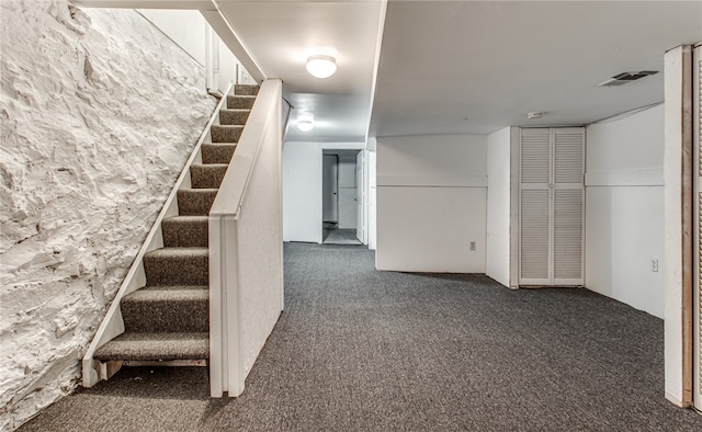 staircase featuring dark colored carpet