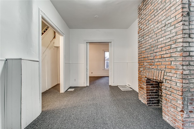 interior space featuring dark colored carpet and brick wall