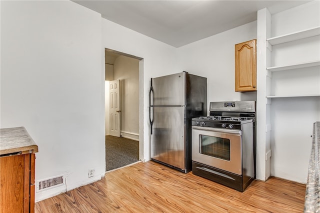 kitchen featuring light carpet, light brown cabinets, stainless steel refrigerator, and gas range